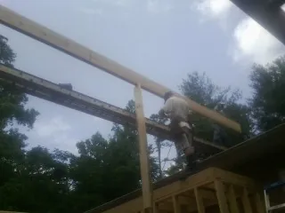 Carpenter setting a ridge beam over a new addition frame — Ice Dam Removal by Roofing Brothers in Carter Lake