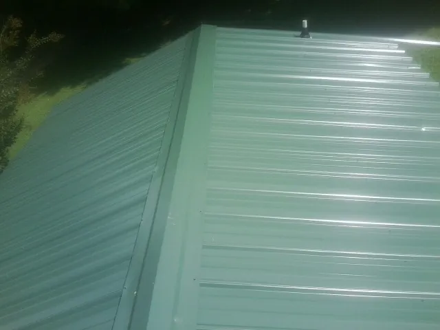 New green metal panels meeting at the ridge of a roof — Flat Roof Repair work by our crew in Carter Lake