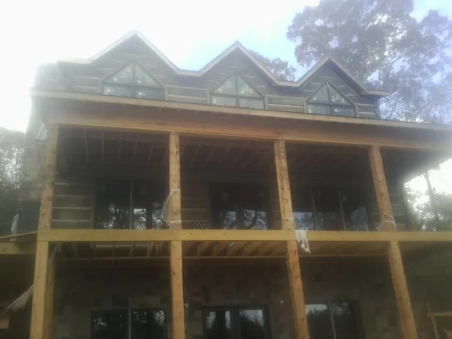 Dormers and porch framing on a large log home under construction — Roof Coating work by our crew in Carter Lake