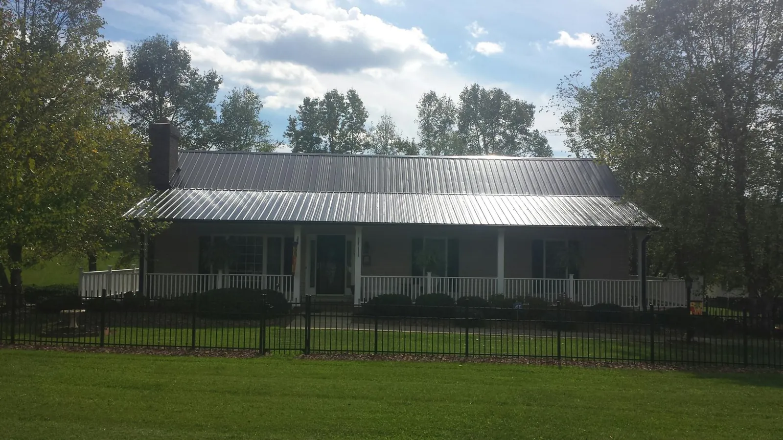 Gray metal roof on a brick ranch with a full width front porch — Gutter Guard Installation work by our crew in Carter Lake
