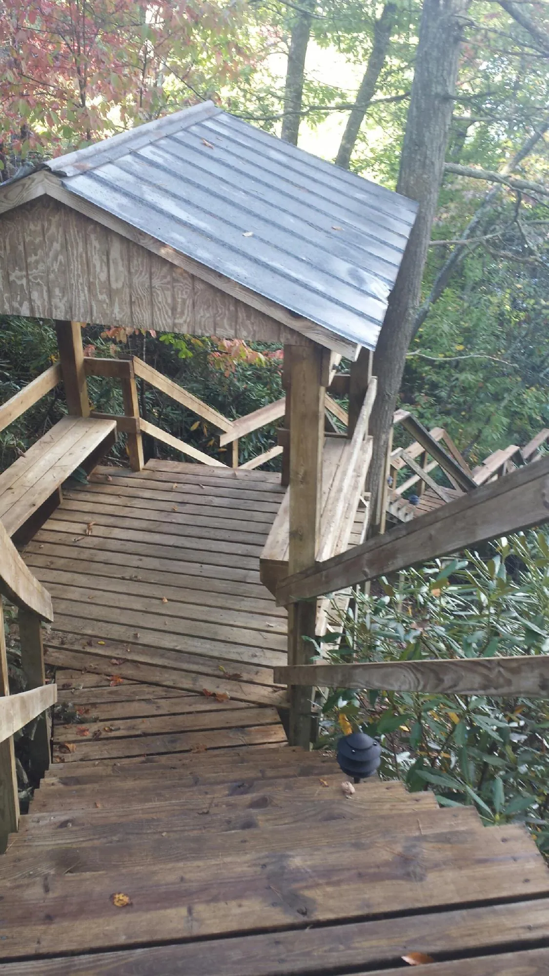 Metal roofed shelter over wooden steps on a wooded walkway — Skylight Repair & Installation work by our crew in Carter Lake