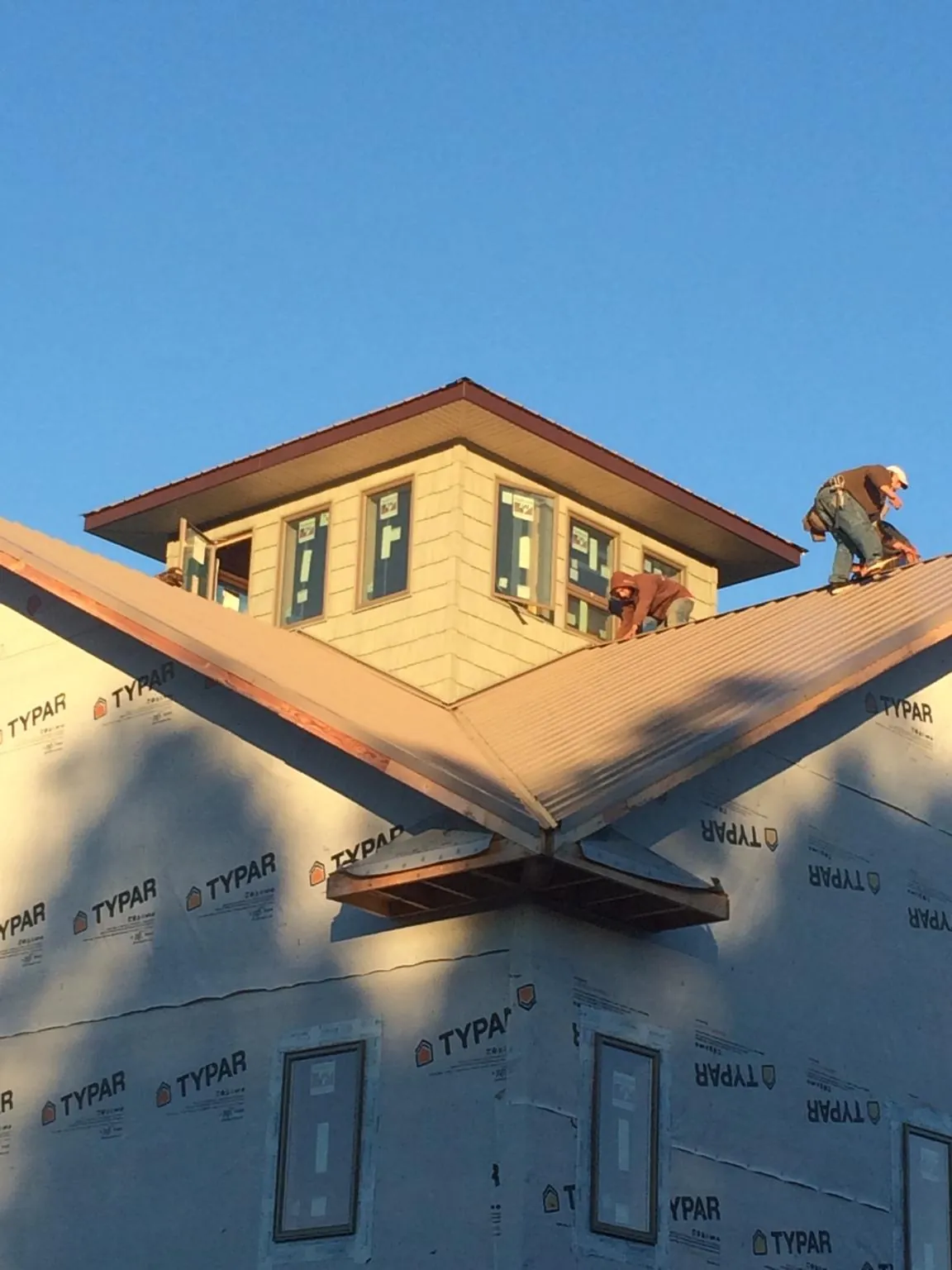 Roofers working around a rooftop cupola on a new metal roof at sunset — Roof Waterproofing in Carter Lake by Roofing Brothers